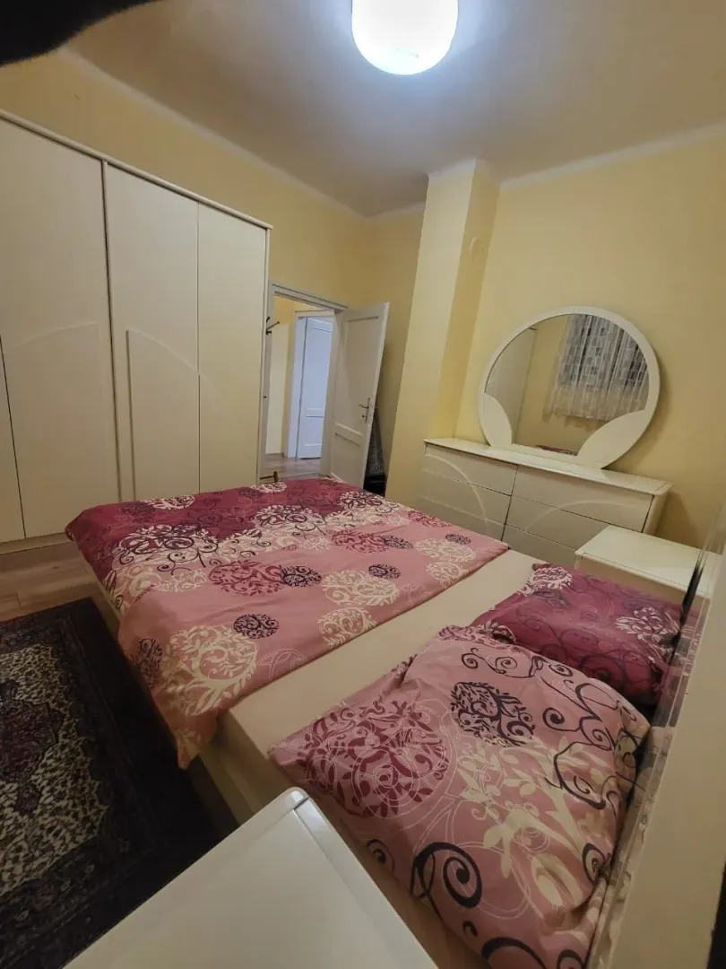 Spavaća soba sa bračnim krevetom, ormarom i toaletnim stolom sa ogledalom.