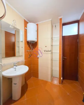 Bathroom tiled in orange and beige with a washbasin and a water heater. - image 7