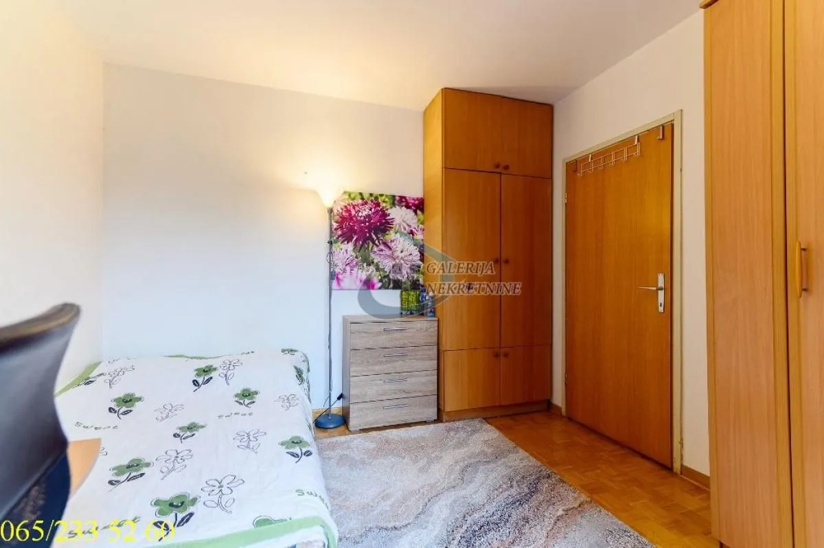 Furnished bedroom with a bed, wooden wardrobes, and laminate flooring.