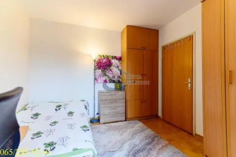Furnished bedroom with a bed, wooden wardrobes, and laminate flooring. - image 12