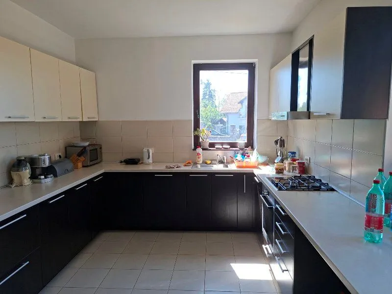 Kuhinja u obliku slova U sa belim gornjim i tamnim donjim elementima, i prozorom iznad sudopere.