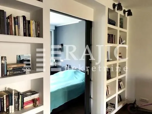 Living room with built-in bookshelves and a view into the bedroom.