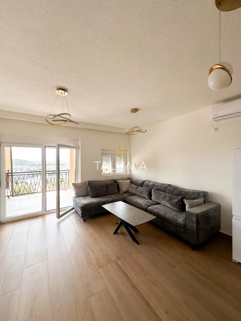 Living room with a sectional sofa, coffee table, and balcony access.