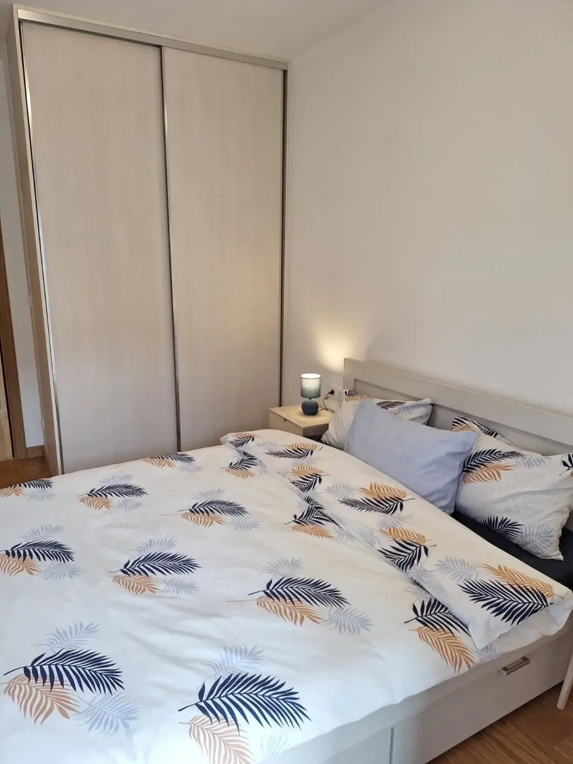 Svijetla spavaća soba sa bračnim krevetom i ugradnim plakarem.