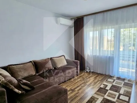 Dnevna soba sa ugaonom garniturom, klima uređajem i prozorom sa bijelim i smeđim zavjesama. - image 4