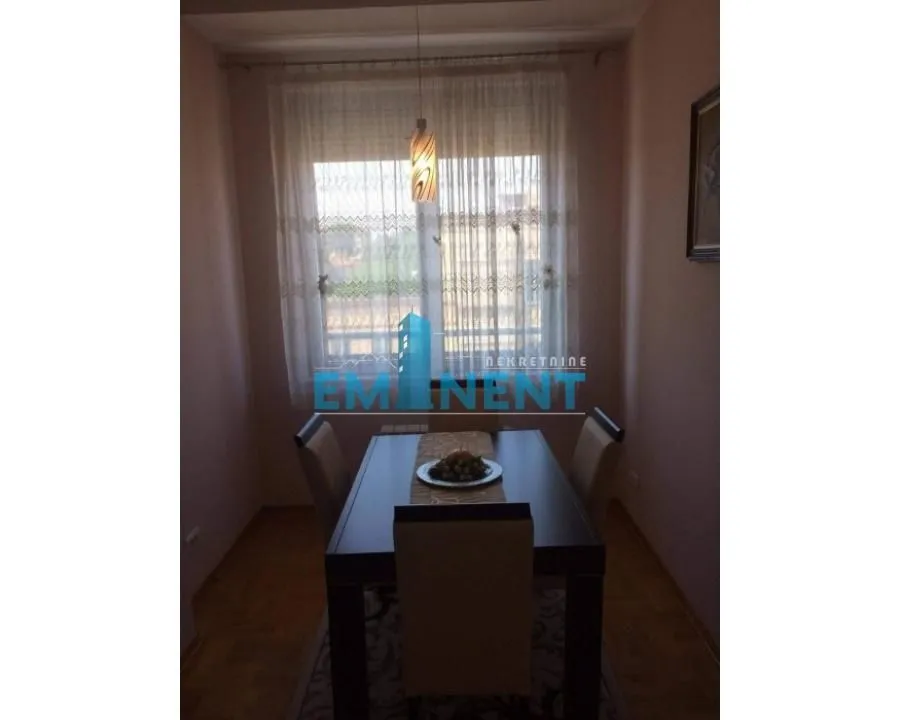 Dining area with a table and chairs in front of the window.
