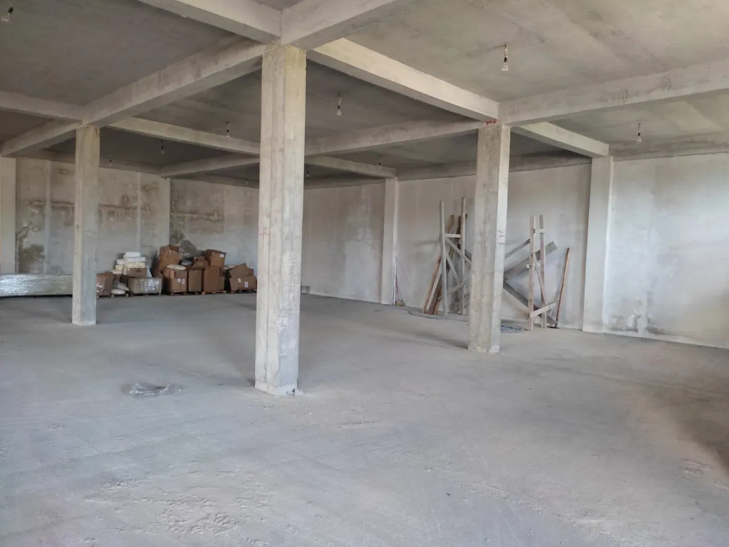 Spacious unfinished interior space in shell stage with concrete pillars.