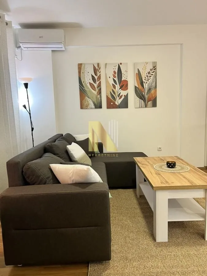 Nameštena dnevna soba sa ugaonom garniturom i stočićem.