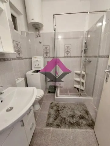 Bathroom with a shower cabin, washbasin, washing machine, and toilet.
