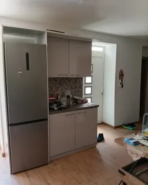 Small kitchen with a refrigerator and cabinets in the living area. - image 6