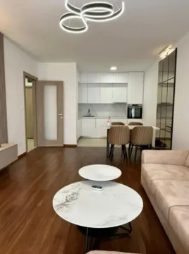 Living room with a sofa, coffee table, and a view of the kitchen and dining area. - image 9