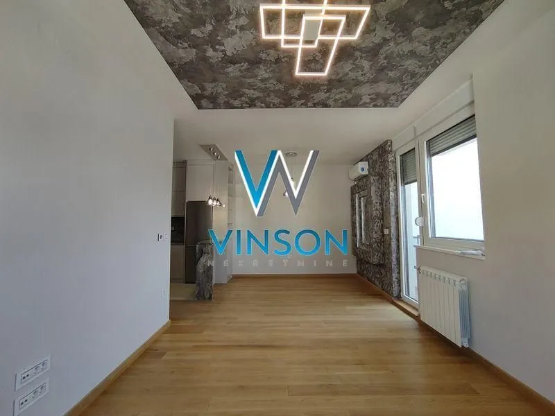 Empty living room with parquet flooring and modern ceiling lighting.