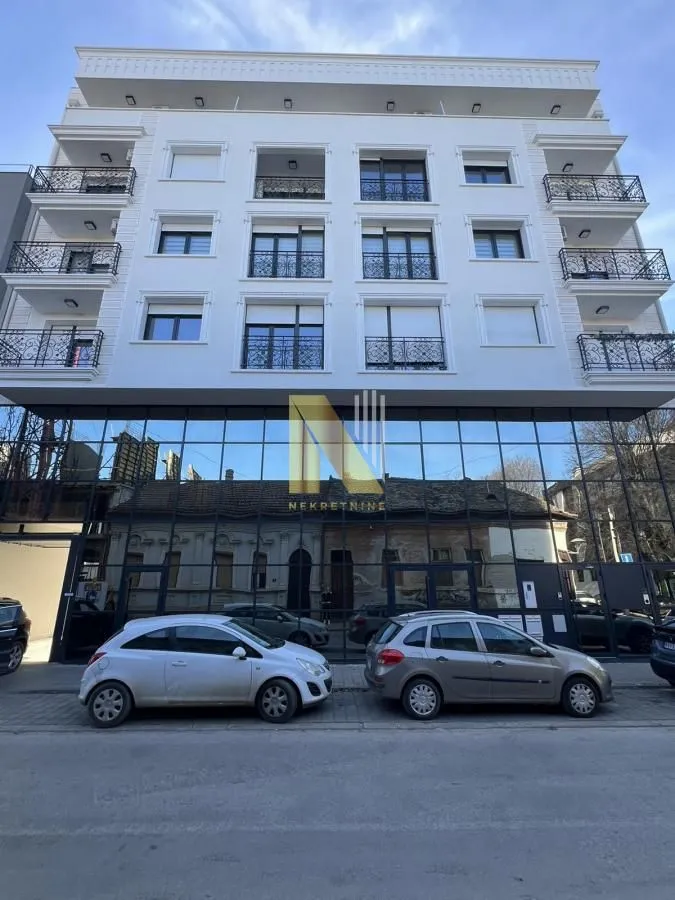 Exterior view of a modern residential building with balconies and a glass ground floor.
