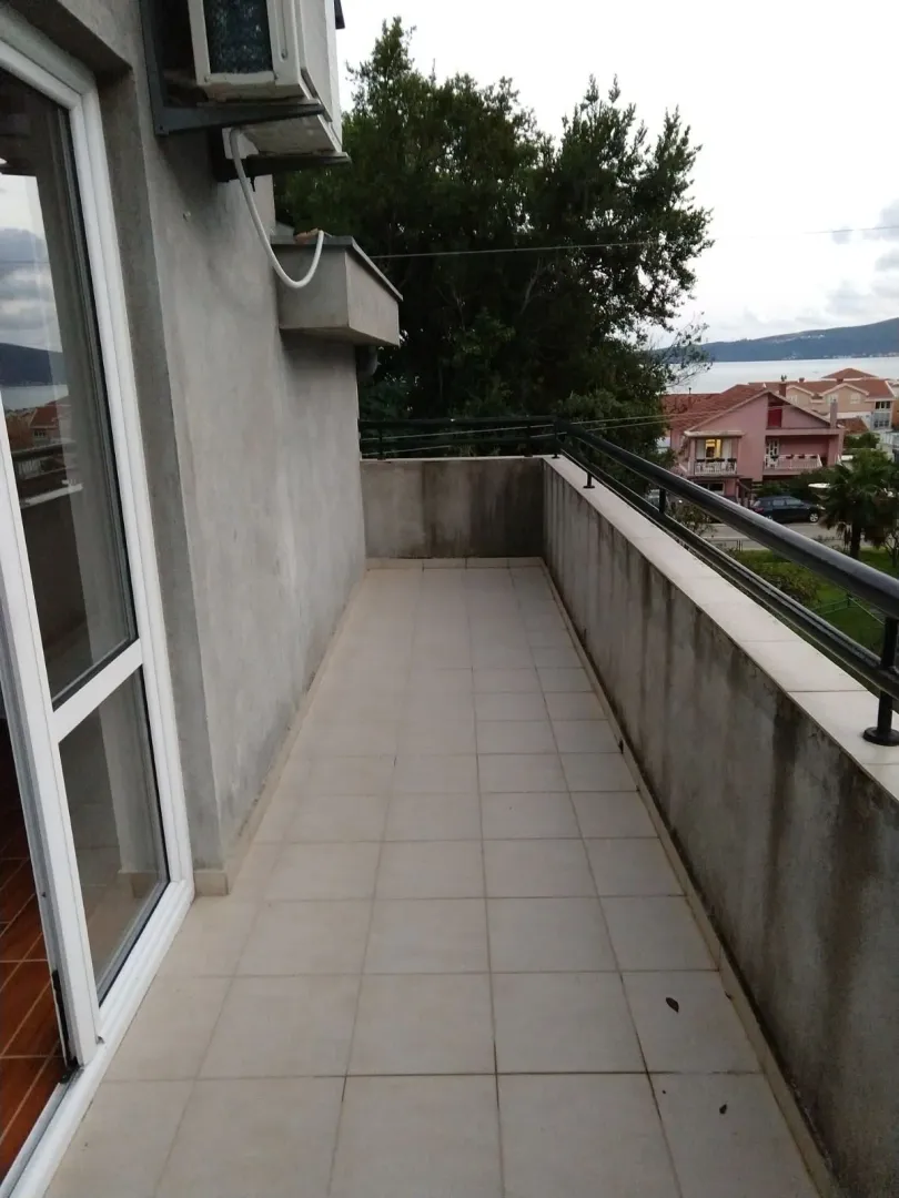 Dugačka terasa sa popločanim podom i pogledom na okolinu.