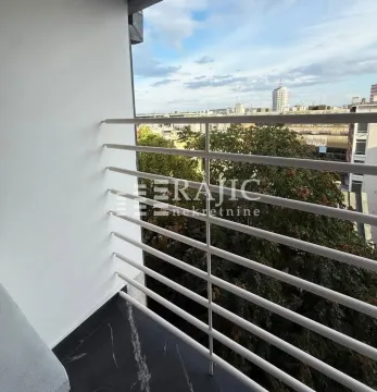 Manji svijetli balkon sa ogradom i pogledom na grad. - image 8