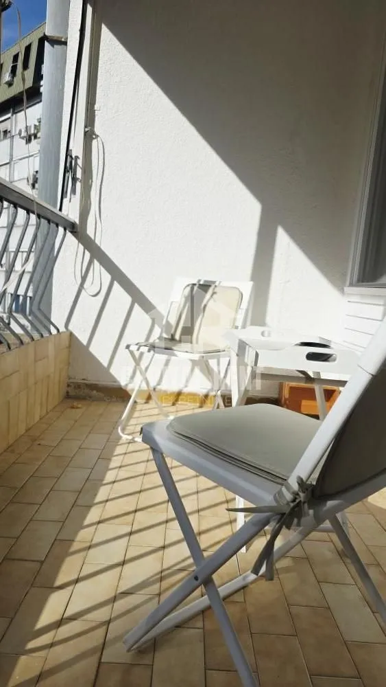 Small furnished balcony with a table and two chairs.