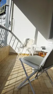 Small furnished balcony with a table and two chairs. - image 12