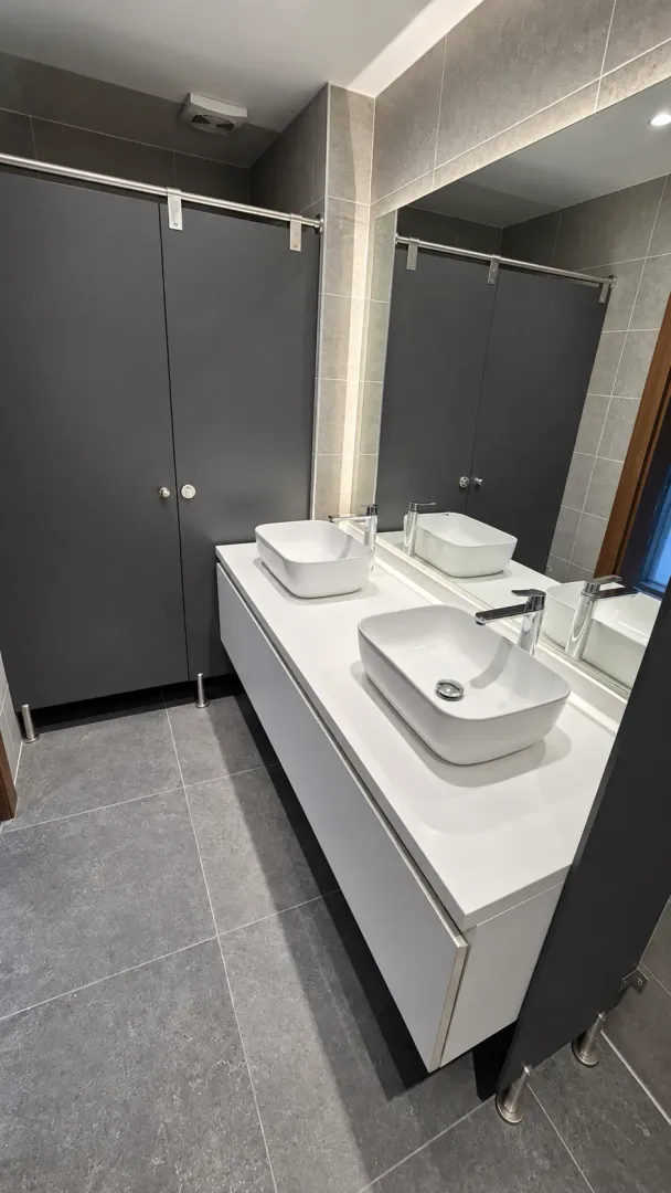 Modernly equipped bathroom with two washbasins and a large mirror.