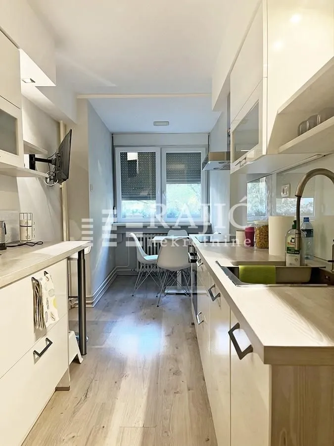 Long white kitchen with a dining area in the back.