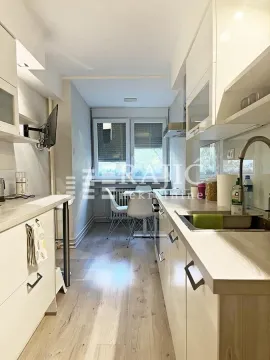 Long white kitchen with a dining area in the back. - image 8