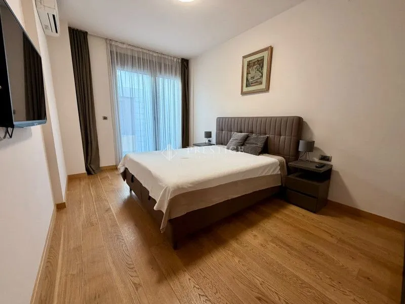Furnished bedroom with a double bed and wooden flooring.
