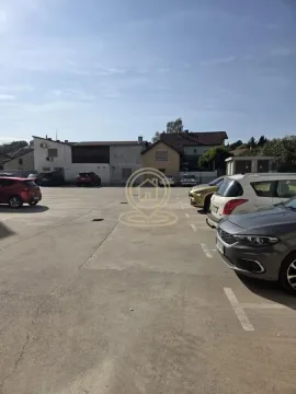 Otvoreni parking prostor sa parkiranim automobilima ispred zgrada. - image 14