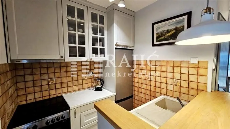 Small equipped kitchen with white cabinets and ceramic tiles.