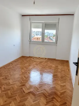 Prazna soba sa parketom i prozorom koji gleda na grad. - image 11