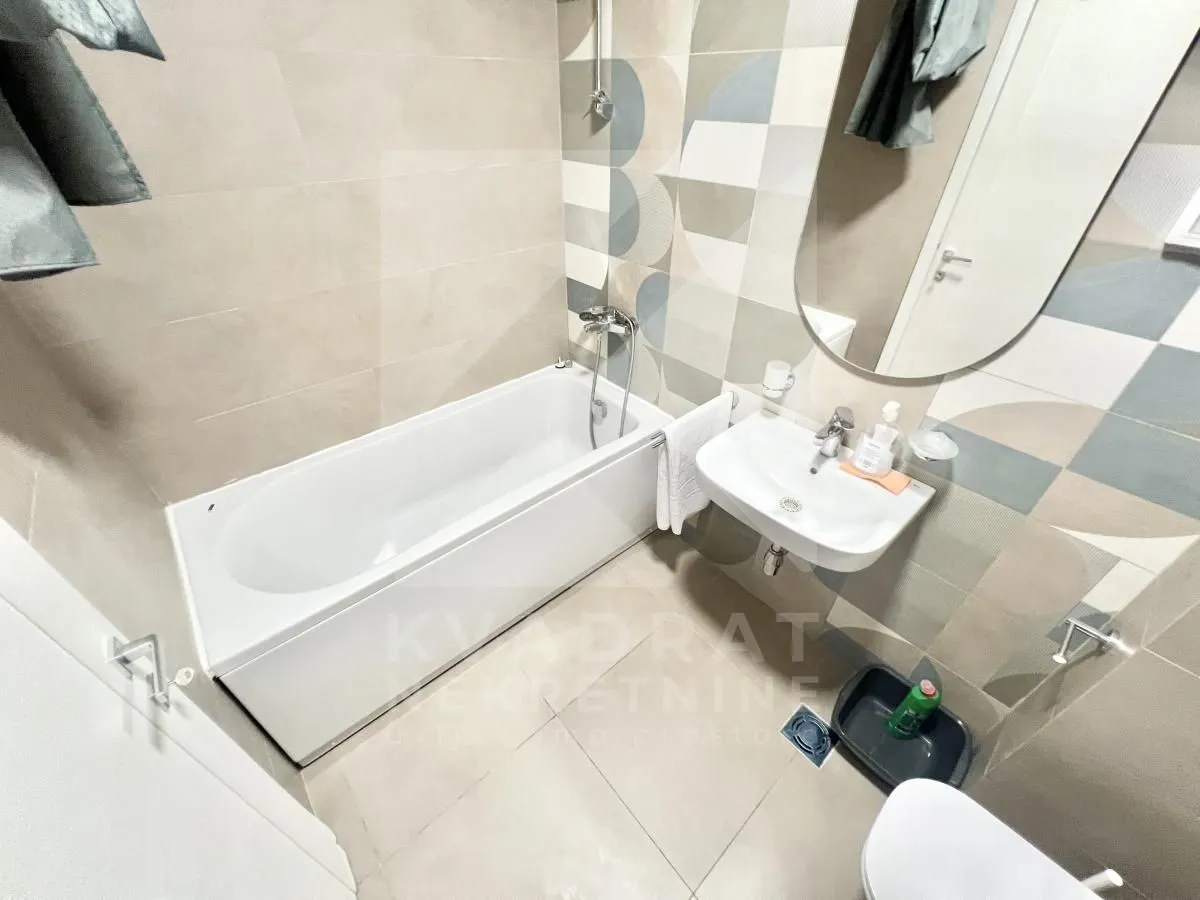 Modernly equipped bathroom with a bathtub, washbasin, and mirror.