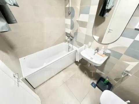 Modernly equipped bathroom with a bathtub, washbasin, and mirror. - image 9