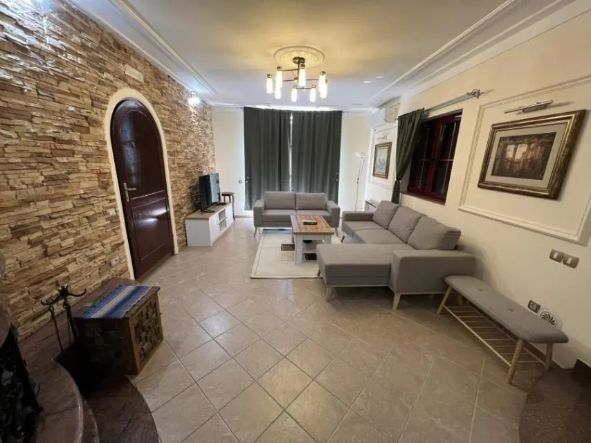 A spacious living room with modern furniture and a decorative stone wall.