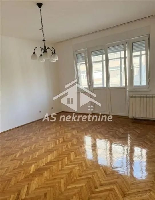 Empty living room with parquet flooring and balcony doors.