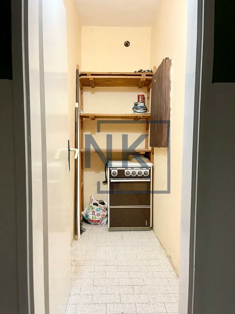 Manja kuhinja sa šporetom i drvenim police.