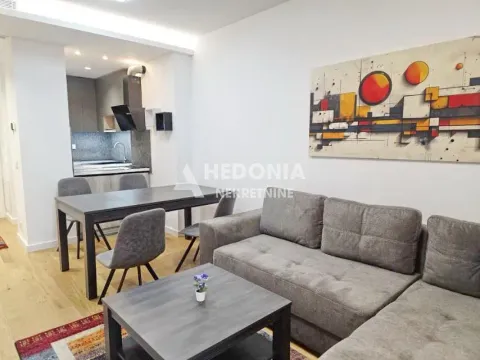 Dnevna soba sa garniturom, stočićem, trpezarijom i kuhinjom u pozadini. - image 8