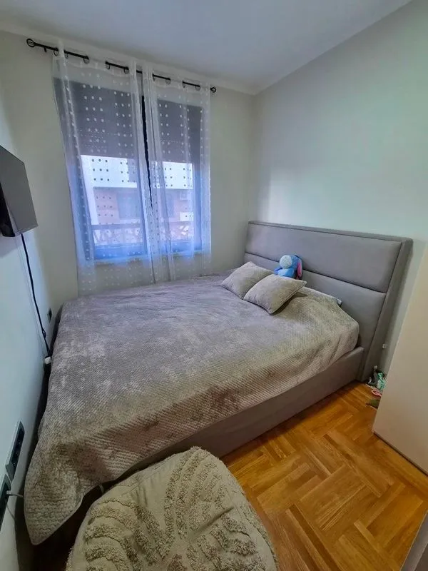 Spavaća soba sa bračnim krevetom i prozorom sa zavesama.