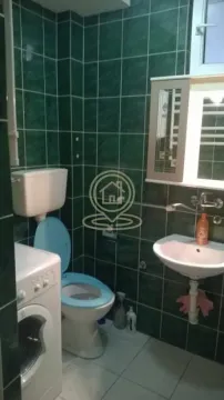 Smaller bathroom with green tiles, toilet, washbasin, and washing machine. - image 8