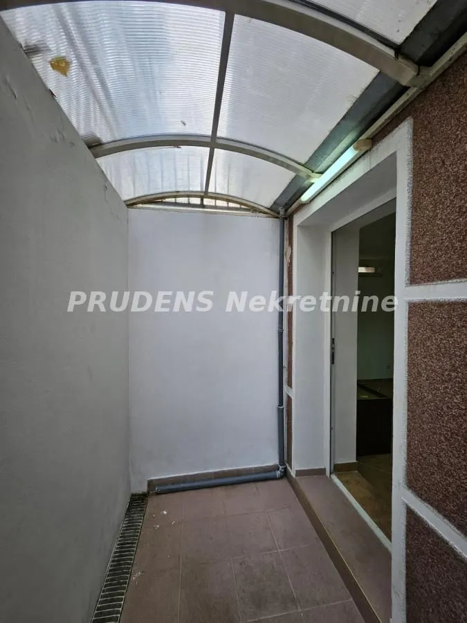 Covered balcony with tiled floor and entrance to the apartment.