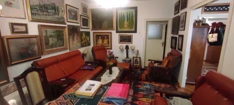 Dnevna soba ispunjena umetničkim slikama na zidovima i garniturom za sedenje. - image 6