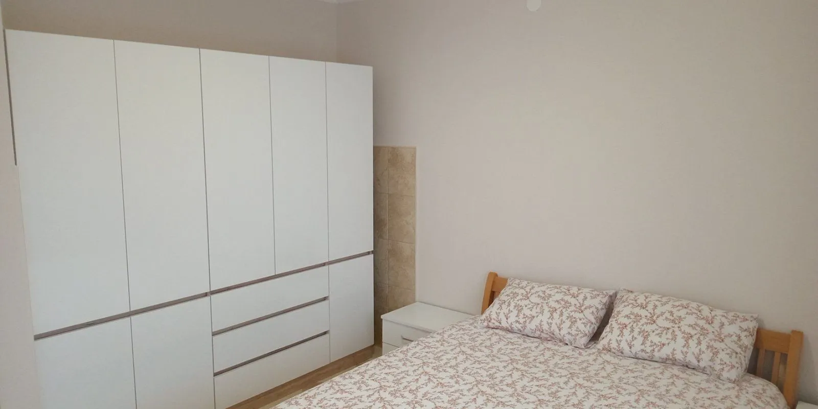 Bedroom with a double bed and a large white wardrobe.