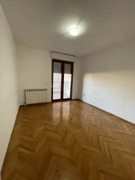 A bright empty room with parquet flooring and balcony doors. - image 4