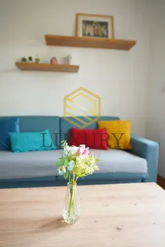 Living room with a blue sofa and wooden shelves on the wall. - image 2