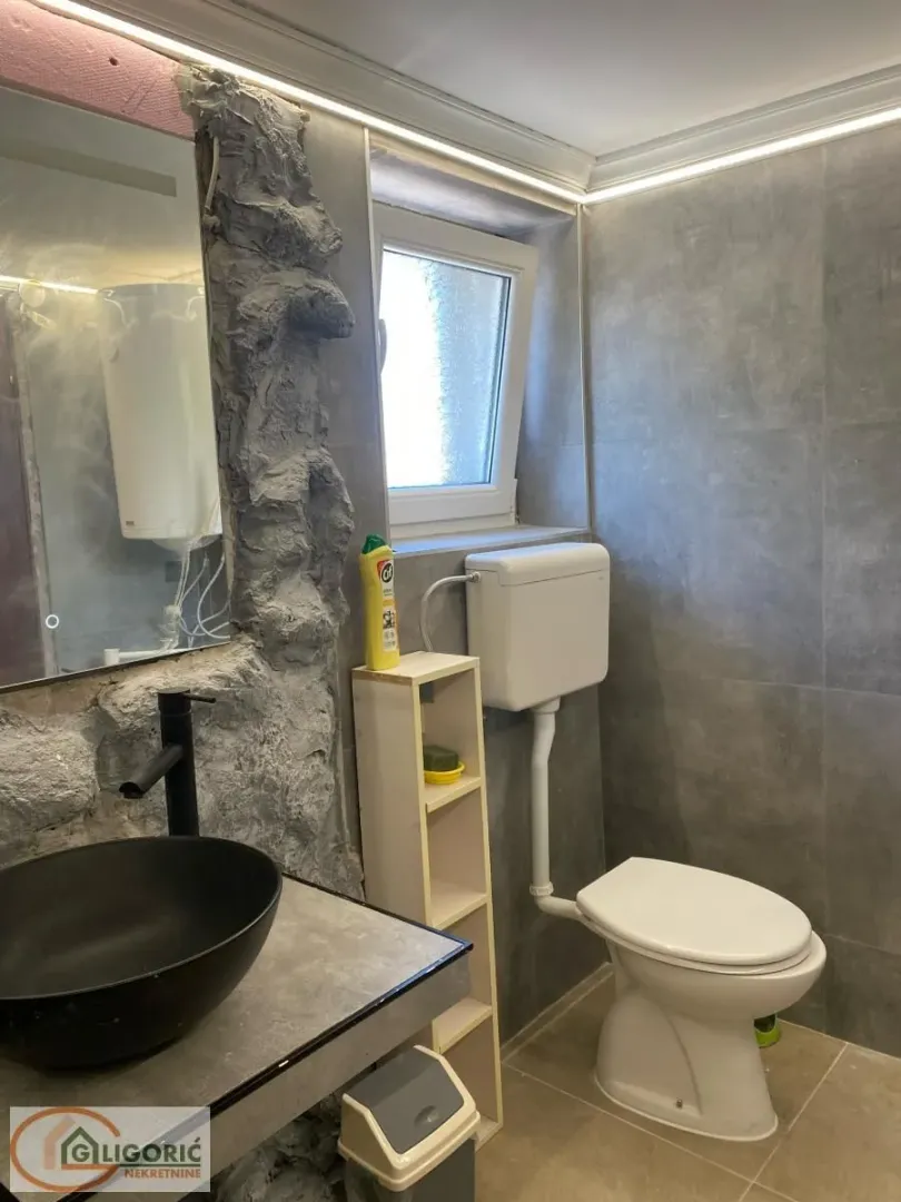 Small bathroom with gray tiles, washbasin and toilet.