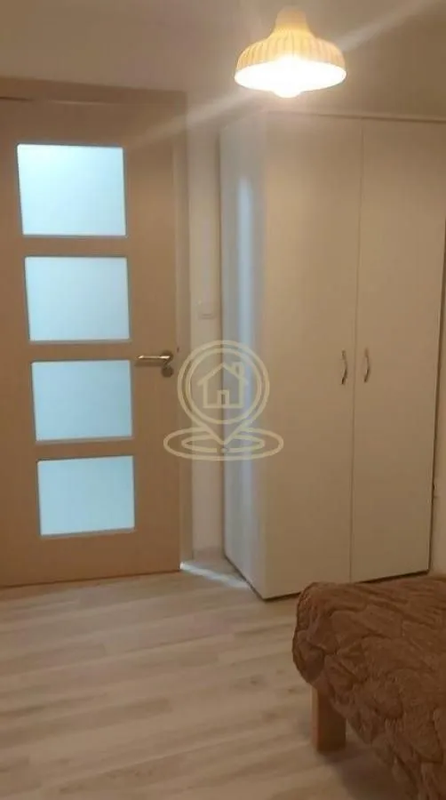 Bedroom with a bed, white wardrobe, and a door.