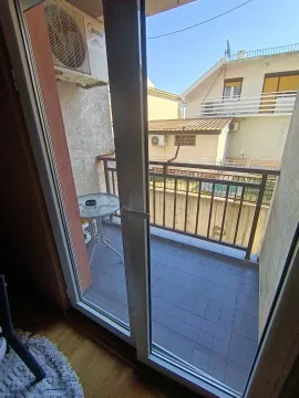 View through the balcony door onto the terrace and surrounding buildings. - image 10
