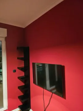Crveni zid sa montiranim televizorom i crnom ugaonom policom. - image 3