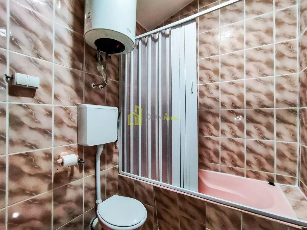 Bathroom tiled with ceramic tiles, featuring a shower cabin and water heater.