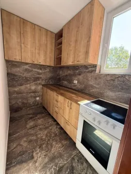 Manja kuhinja sa drvenim elementima, tamnim keramičkim pločicama i šporetom. - image 6