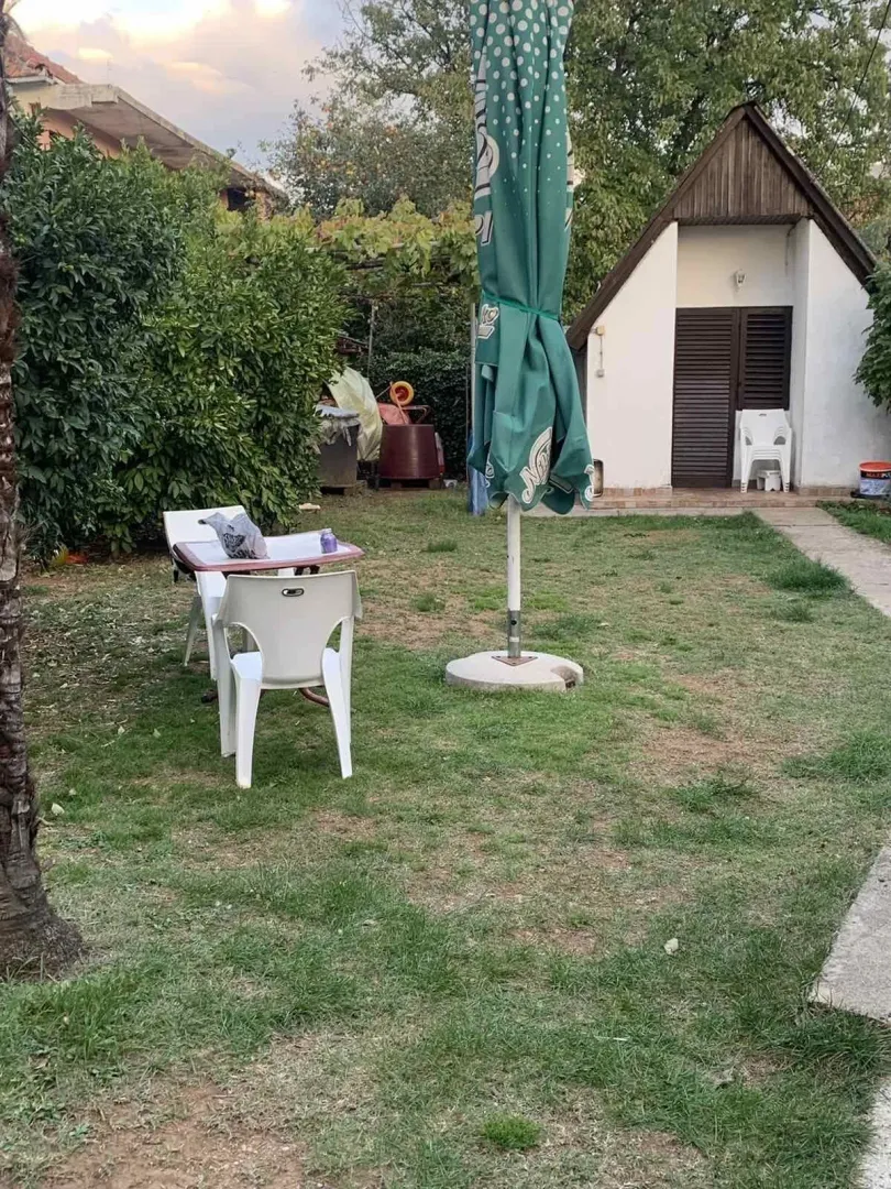 A spacious yard with a lawn, outdoor seating, and an auxiliary building in the background.