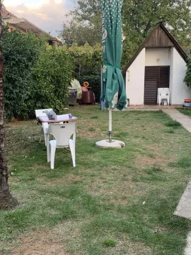 A spacious yard with a lawn, outdoor seating, and an auxiliary building in the background. - image 6