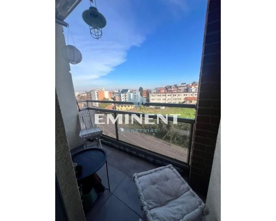 Namešten balkon sa stolom, stolicom i pogledom na grad.